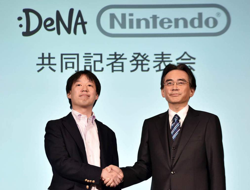 Japan's video game giant Nintendo president Satoru Iwata (R) shakes hands with Japanese online game operator DeNA president Isao Moriyasu during a press conference in Tokyo on March 17, 2015. Nintendo said on March 17 it was teaming up with a mobile gaming company to develop games for smartphones in what could be a turning point for the Japanese giant which has long refused to enter the soaring market. AFP PHOTO / Yoshikazu TSUNO (Photo credit should read YOSHIKAZU TSUNO/AFP/Getty Images)